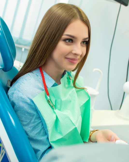 woman in dental chair smiling and listening to dentist