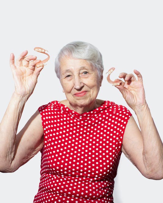senior woman holding dentures