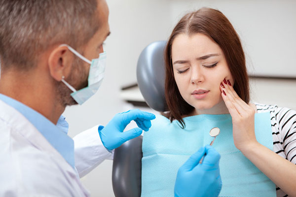 young woman at the dentist holding her mouth in pain