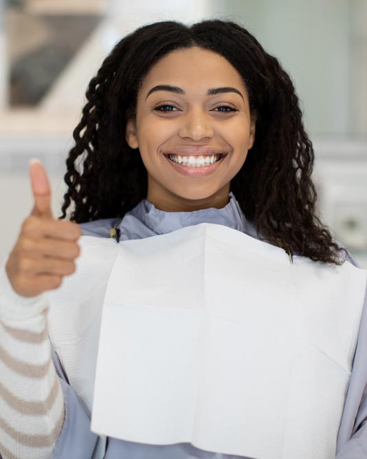 woman in dental chair giving thumbs up and smiling