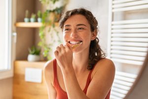 woman smiling while brushing her teeth