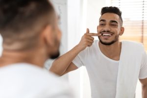 man looking at his teeth in the mirror