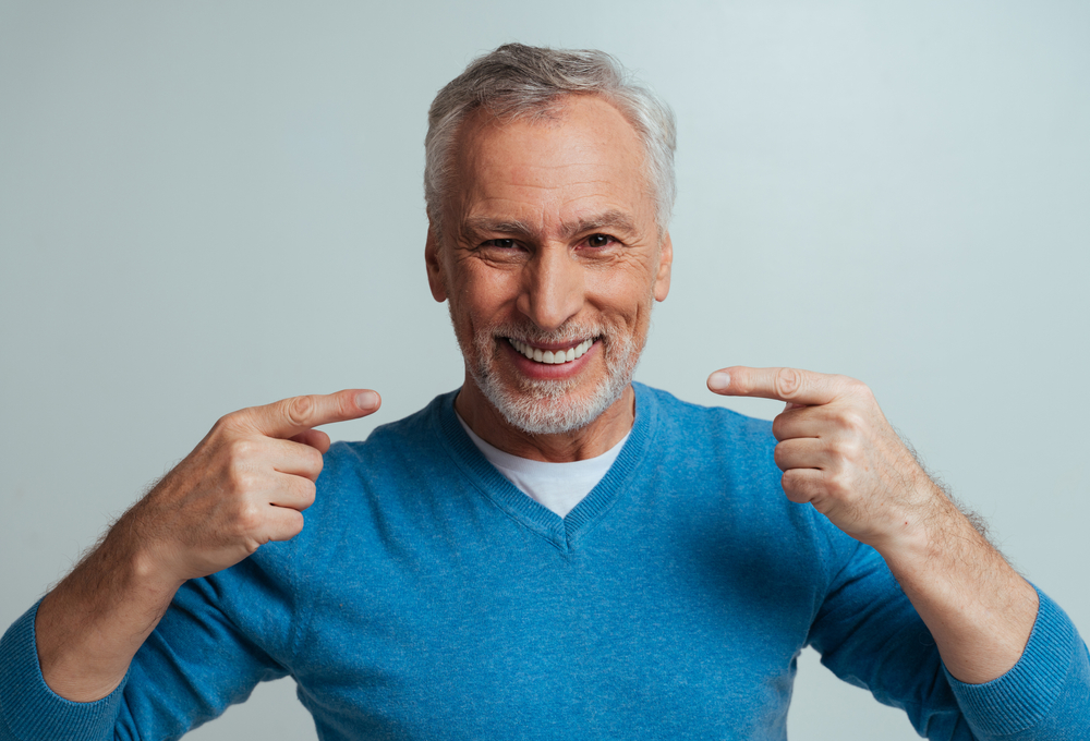 man pointing at smile with dentures