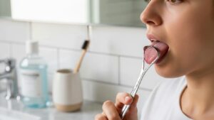 person-using-a-tongue-scraper-in-a-bathroom-highlighting-the-importance-of-tongue-cleaning-for-fresh-breath